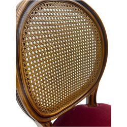 Set six French style walnut finish dining chairs, oval cane bergere backs over serpentine seats upholstered in red, flower head carved fluted supports