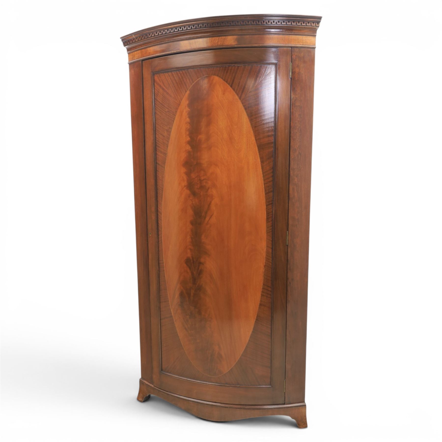 Edwardian inlaid mahogany cylindrical corner hall-robe, projecting cornice, figured veneer and crossbanded door, enclosing hanging hooks and shelf, raised on a plinth base with bracket feet