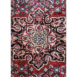 Persian design crimson ground rug, the field decorated with central floral pole medallion and surrounded by foliate patterns with matching spandrels, guarded border with repeating palmette motifs