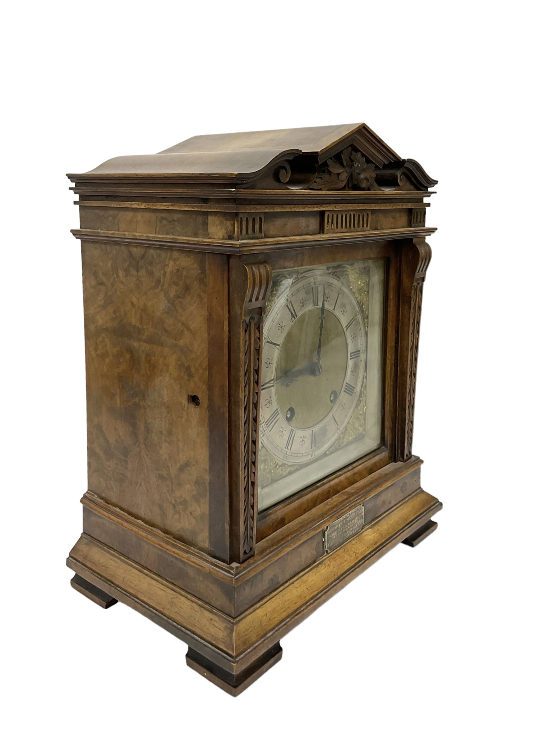 Lenzkirch - Late 19th century 8-day German mantle clock in a walnut veneered case with an architectural pediment, square brass dial, cast spandrels, matted dial centre, silvered chapter ring and fleur-di-Lis hands, with a twin train movement chiming the quarters on two coiled gongs and striking the hours on one. With Key and pendulum. Silver presentation plaque dated 1896.