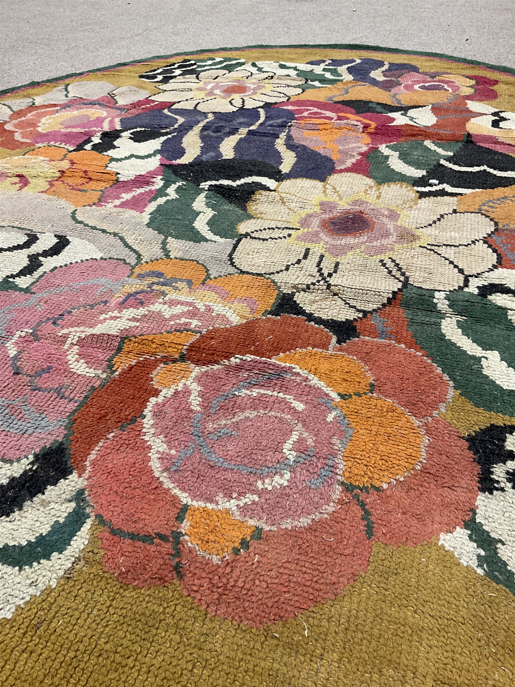 20th century wool oval rug, mustard ground and decorated with flower heads, with pink and green outer bands
