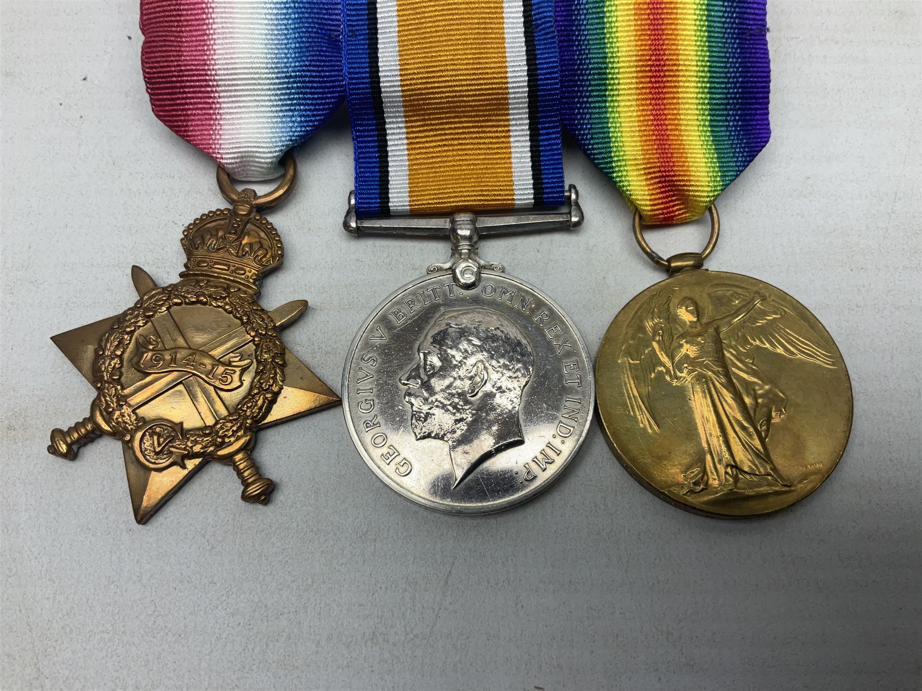 WW1 KIA group of three medals comprising British War Medal, 1914-15 Star and Victory Medal awarded to 9069 Cpl. J. Mayhew Glouc. R.; with ribbons; displayed on modern bar, and photograph of recipient in uniform; some biographical details
