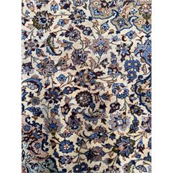 Central Persian Najafabad hand-knotted carpet, the ivory field with a central floral medallion radiating palmettes and arabesques in tones of blue, lilac and tan, enclosed by a wide navy border of scrolling vine and rosette motifs, with red spandrels and multiple guard stripes