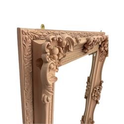 Rectangular wall mirror, in ornate pale pink painted frame decorated with scrolled foliage, flower head and shell motifs, bevelled plate