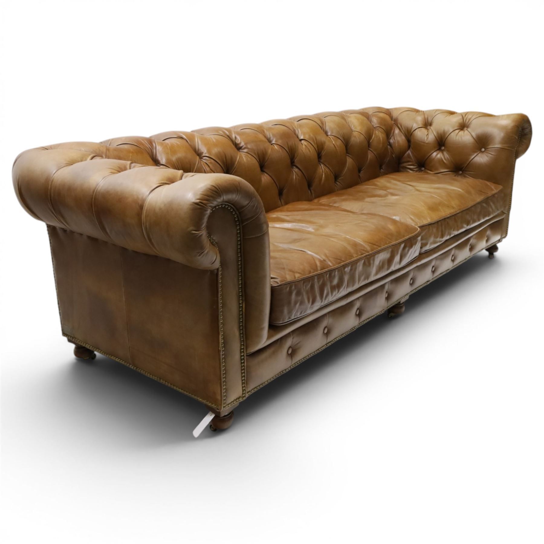 Timothy Oulton for HALO - Three seater brown leather chesterfield sofa, with button back and arms, with two loose cushions, raised on a dark stained supports terminating in castors 