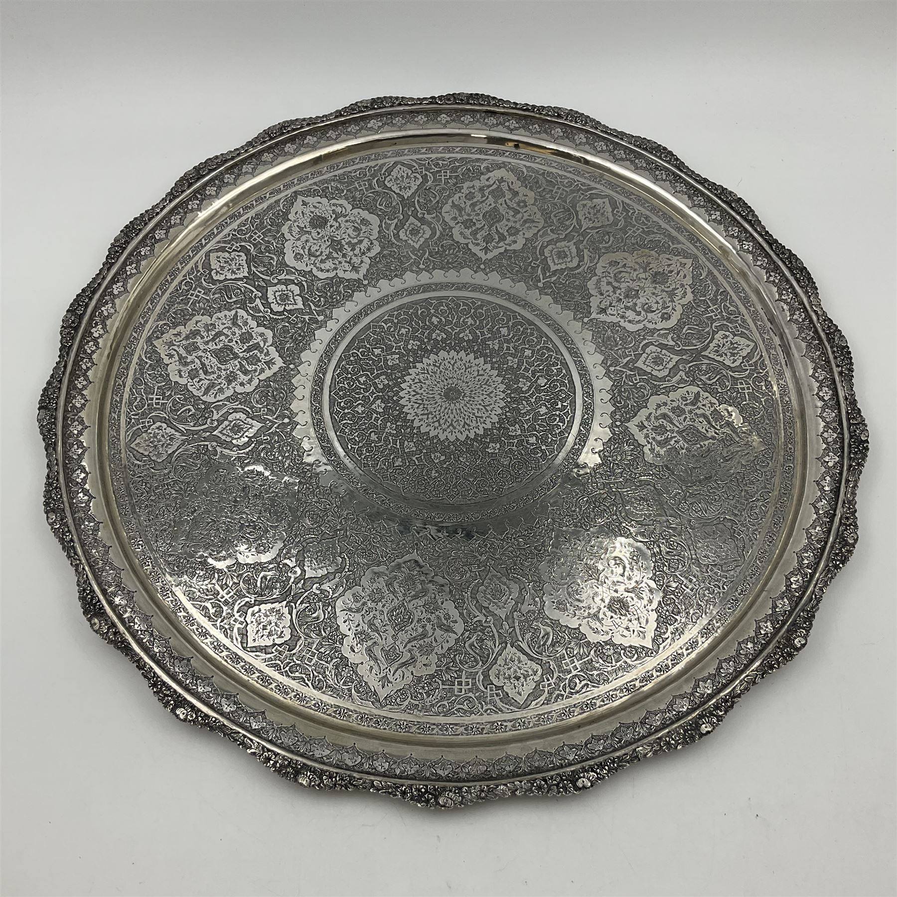 Early/mid 20th century Persian silver tea service, comprising circular serving tray, teapot, twin handled sucrier and cover, milk jug, five tea glasses with six silver holders, six tea spoons, and pair of sugar tongs, each profusely chased with foliate arabesque decoration, each bearing marks including 84 for 840 fineness, tray D40cm, teapot H16cm