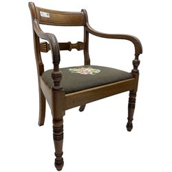 Regency mahogany elbow chair, carved shaped central back bar, over drop-in seat upholstered in floral needlework, raised on ring turned front supports