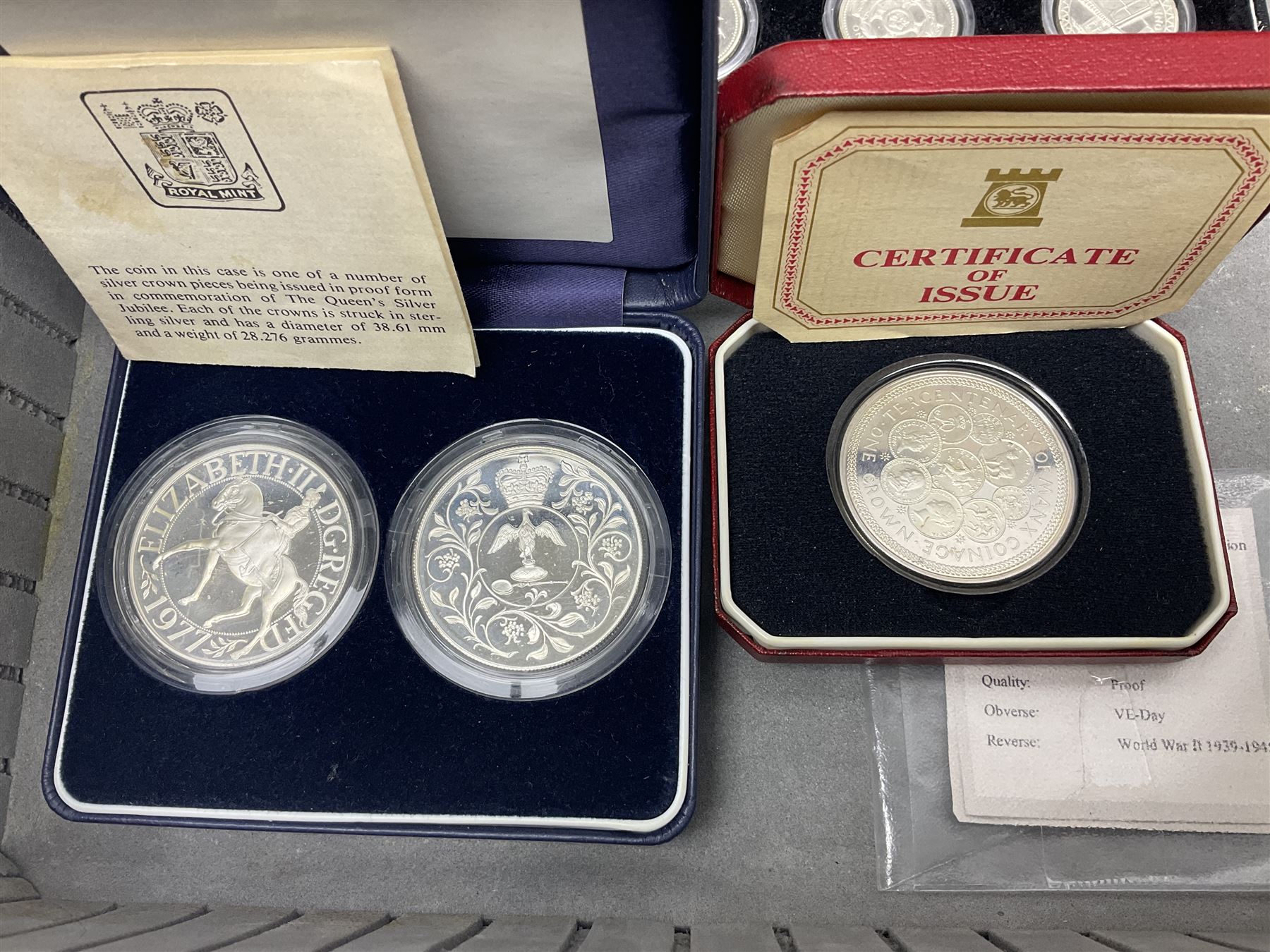 The Royal Mint United Kingdom 1977 silver proof two coin set, Queen Elizabeth II 2002 silver proof three coin set, comprising Bailiwick of Jersey, Bailiwick of Guernsey, and Alderney five pound coins, 'First Coinage of the British Virgin Islands' proof set, 1997 1/10 ounce fine silver Britannia, two King George V 1935 'Rocking Horse' crowns, various Isle of Man commemorative crowns, etc., house in a hard shell carry case