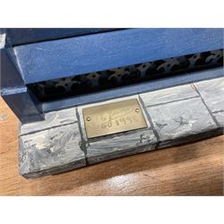 Good quality late 20th century dolls house by M. James dated 1995 in the form of a Beverley East Yorkshire Antique Shop called 'North Bar Antiques'; single-storey single-roomed shop with textured brick walls and flat roof, fully glazed hinged front with recessed hinged customer door and central window to the rear; comprehensively furnished with chests of drawers, pedestal desk, breakfast table, lowboy, two longcase clocks, delft rack with ceramics, occasional tables, pictures, Regency style mirror and collectibles; decorated walls with coving and picture rail and simulated floorboarding; wired for electric lighting; maker's plaque W61cm H42.5cm D41.5cm