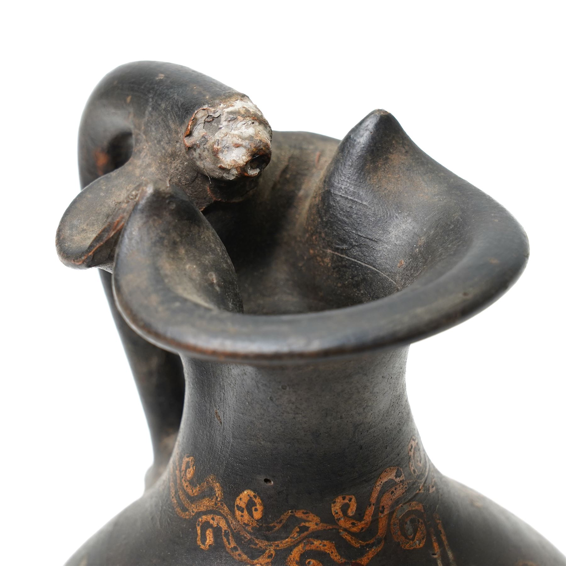 South Italian Gnathian terracotta oinochoe (jug) Apulian or Campanian (Late 4th century BC c.325-300 BC) of elegant ovoid form with trefoil mouth and single strap handle, the handle terminating in a stylised serpentine motif merging into the pouring lip, the vessel covered in a black gloss slip and decorated in added red, white and yellow with a theatrical mask, fillets and scrolling Dionysiac vine motifs, H19cm 
Notes: Gnathian ware takes its name from Egnathia in Apulia and is characterised by a black-gloss ground with added-colour decoration; the theatrical mask, fillets and vine scrolls relate to Dionysiac imagery associated with the symposium and theatre in South Italian Greek culture of the late fourth century BC. A very similar oinochoe is held in the The Metropolitan Museum of Art, object number 76.12.8