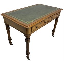Victorian oak writing table, rectangular top with green leather inset writing surface, fitted with two drawers, raised on turned and fluted supports terminating in brass cups and castors