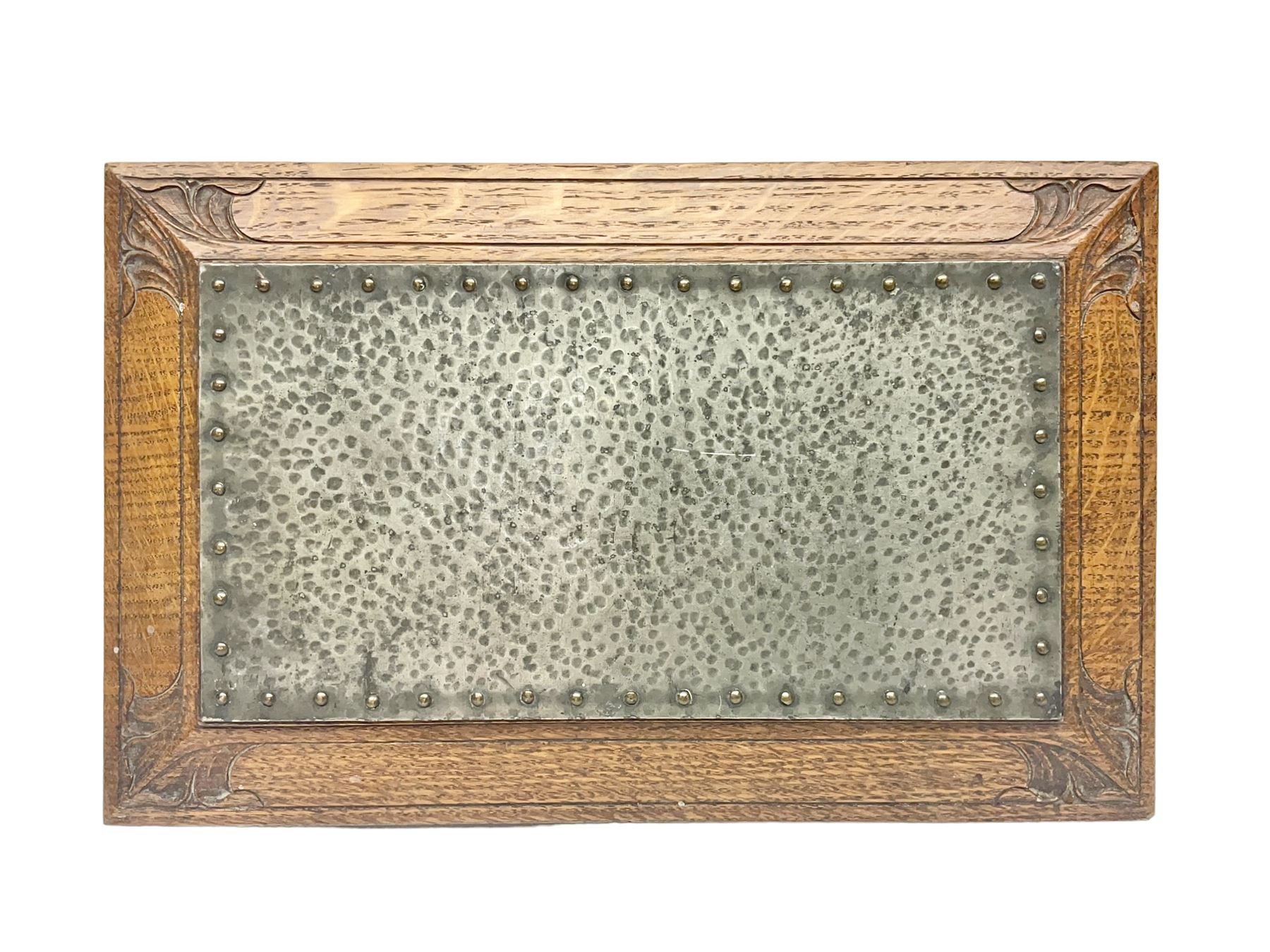 Arts and Crafts oak stand by Arthur Simpson of Kendal, of rectangular form with central hammered pewter panel, surrounded by a border with carved foliate corners, upon two bar supports, bearing label detailed 
