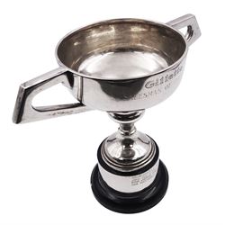 Mid 20th century silver trophy cup, the bowl with twin angular handles and presentation engraving, upon a knopped stem, spreading foot, and black cylindrical plinth, hallmarked Viner's Ltd, Sheffield 1960, trophy cup H15cm overall H20.5cm, approximate gross weight of cup (with screw fixings but not including black base) 10.15 ozt (315.8 grams)
