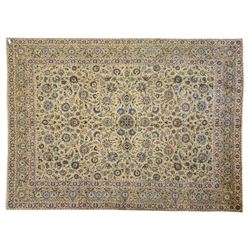 Persian Kashan carpet, beige ground, field with an all-over design of scrolling palmettes and floral sprays in blue and terracotta within a ivory ground and pale blue floral border