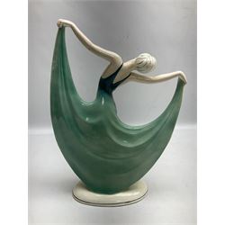 Early 20th century Hertwig Katzhütte figure of an Art Deco lady dancing, wearing a green, blue and yellow dress, stood upon on a domed plinth, with green cat H house printed mark beneath, H32cm