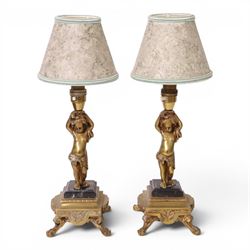 Pair of brass table lamps, the central column modeled as a putti upon a square marble base...