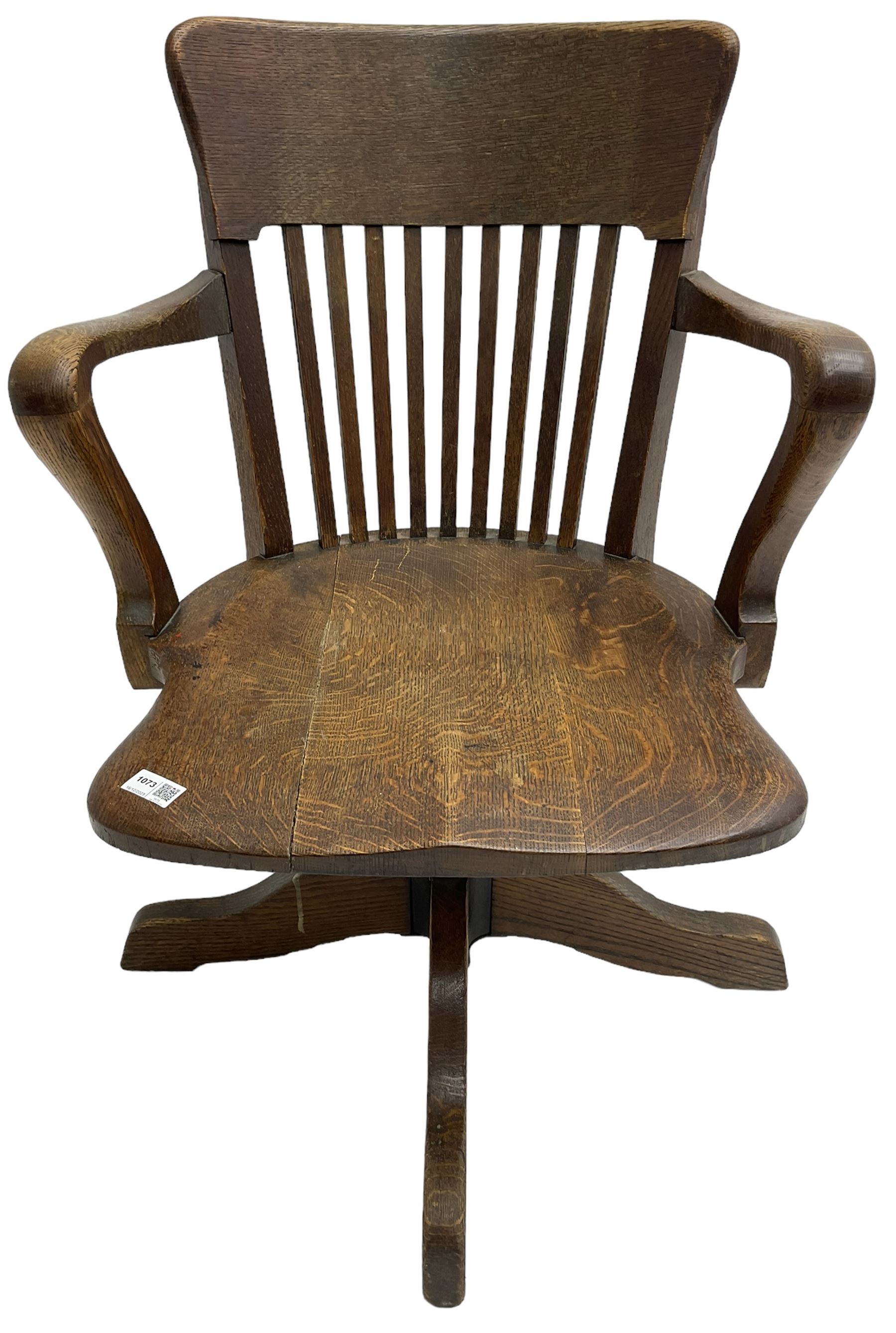 Early 20th century swivel office desk chair, shaped bar back over vertical rails, dished seat, on four splayed supports