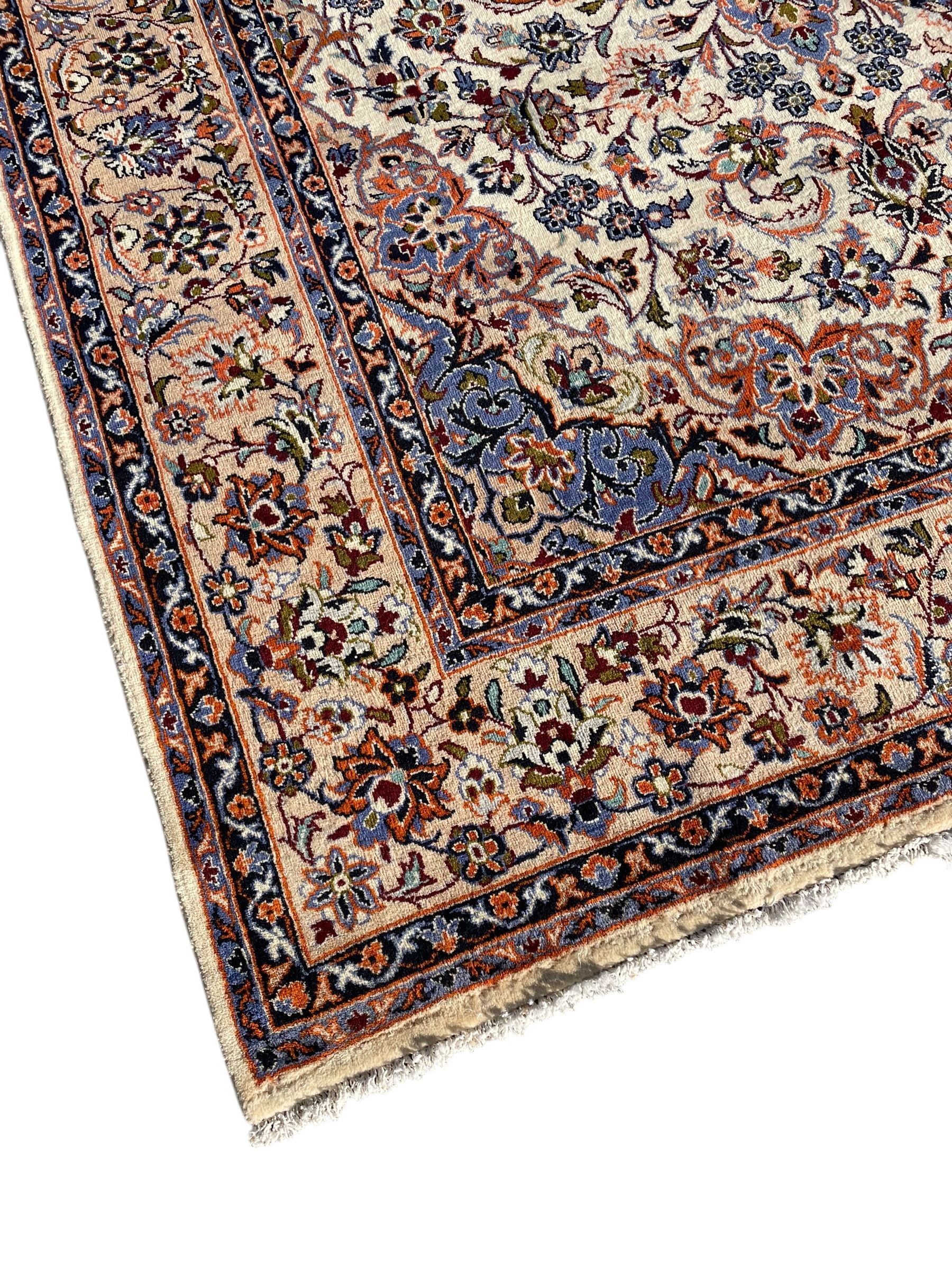 Persian Najafabad ivory and peach ground rug, central rosette medallion surrounded by swirling leafy branches and palmettes, trailing border decorated with stylised plant motifs, enclosed within floral pattern guard stripes