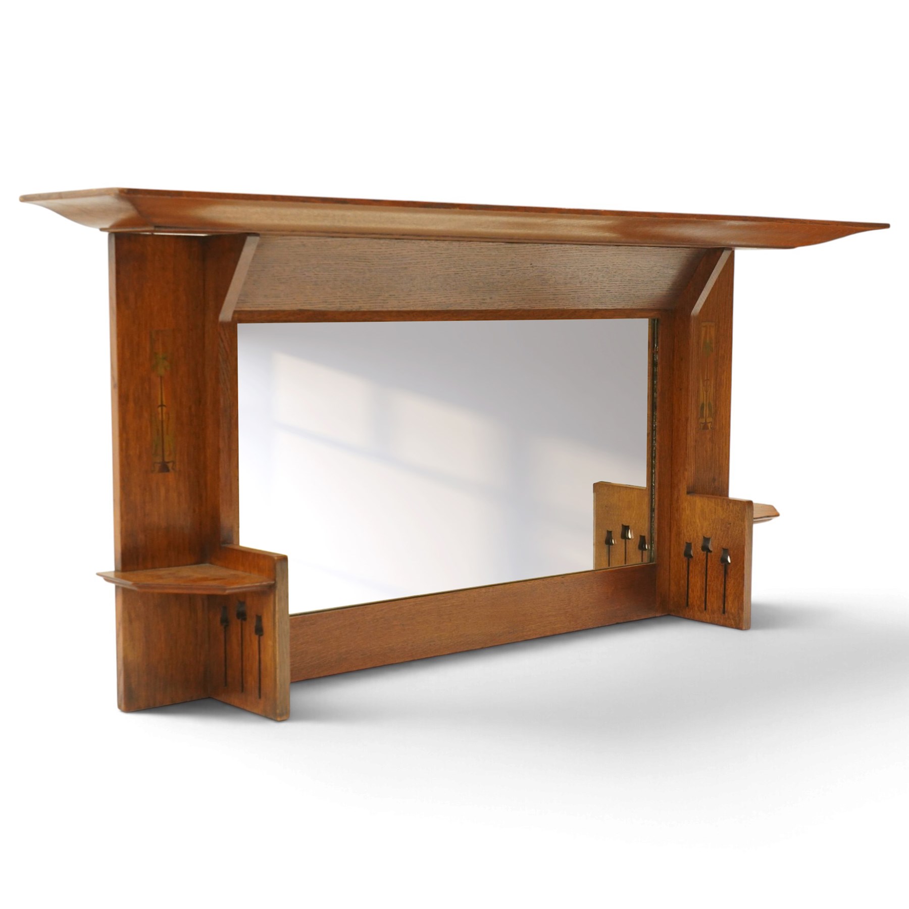Manner of Liberty & Co, - Arts & Crafts inlaid oak overmantel mirror, the deep-projecting cornice over a rectangular plate, flanked by Art Nouveau marquetry panels of stylised tulip and foliate motifs, over a canted shelf and tulip-pierced upright