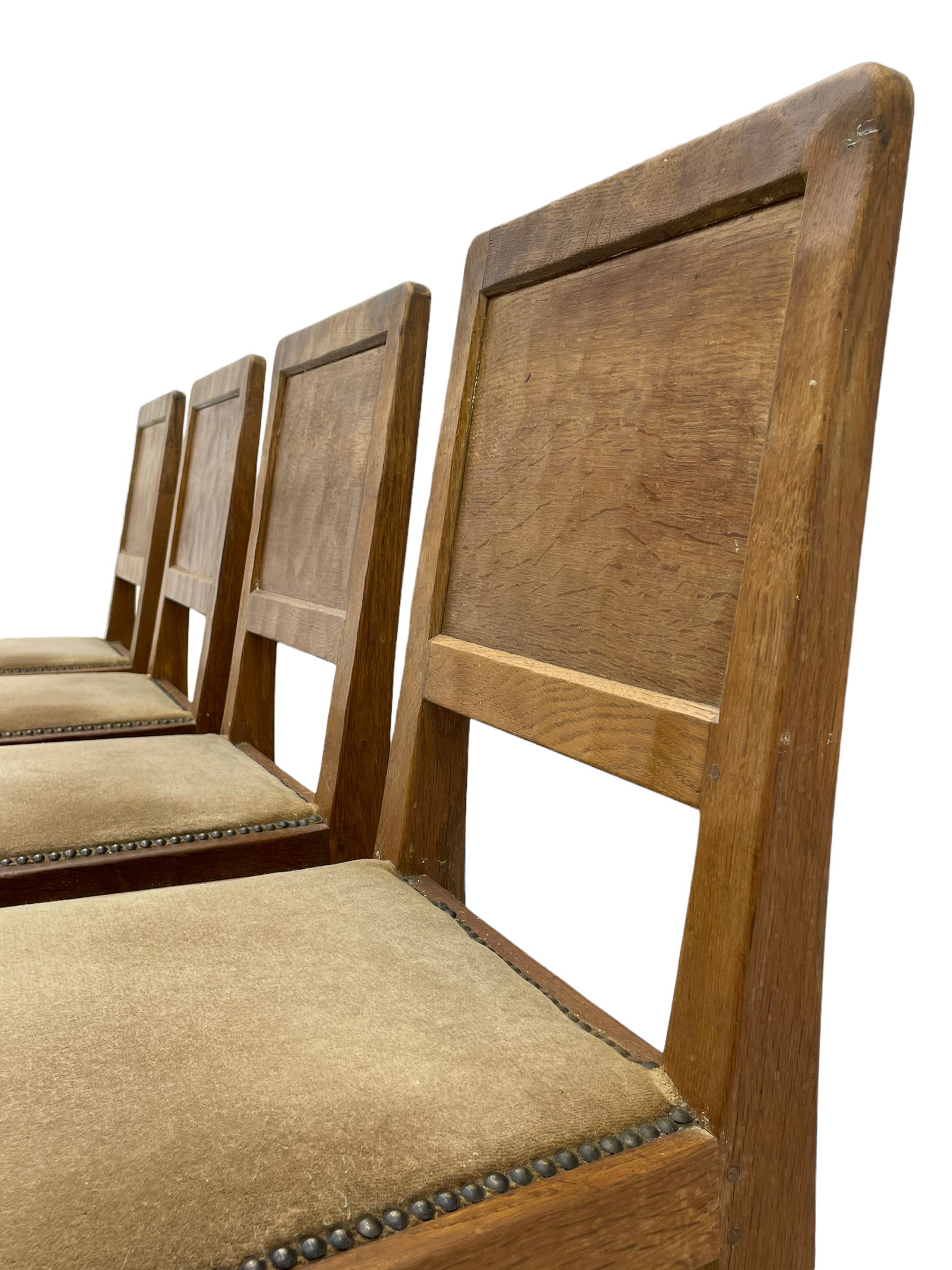 'Eagleman' set four oak dining chairs, adzed panelled backs, upholstered seats with stud work band, the side rails relief carved with inset eagle signature, shaped octagonal supports joined by stretchers, by Albert Jeffray of Sessay, Thirsk