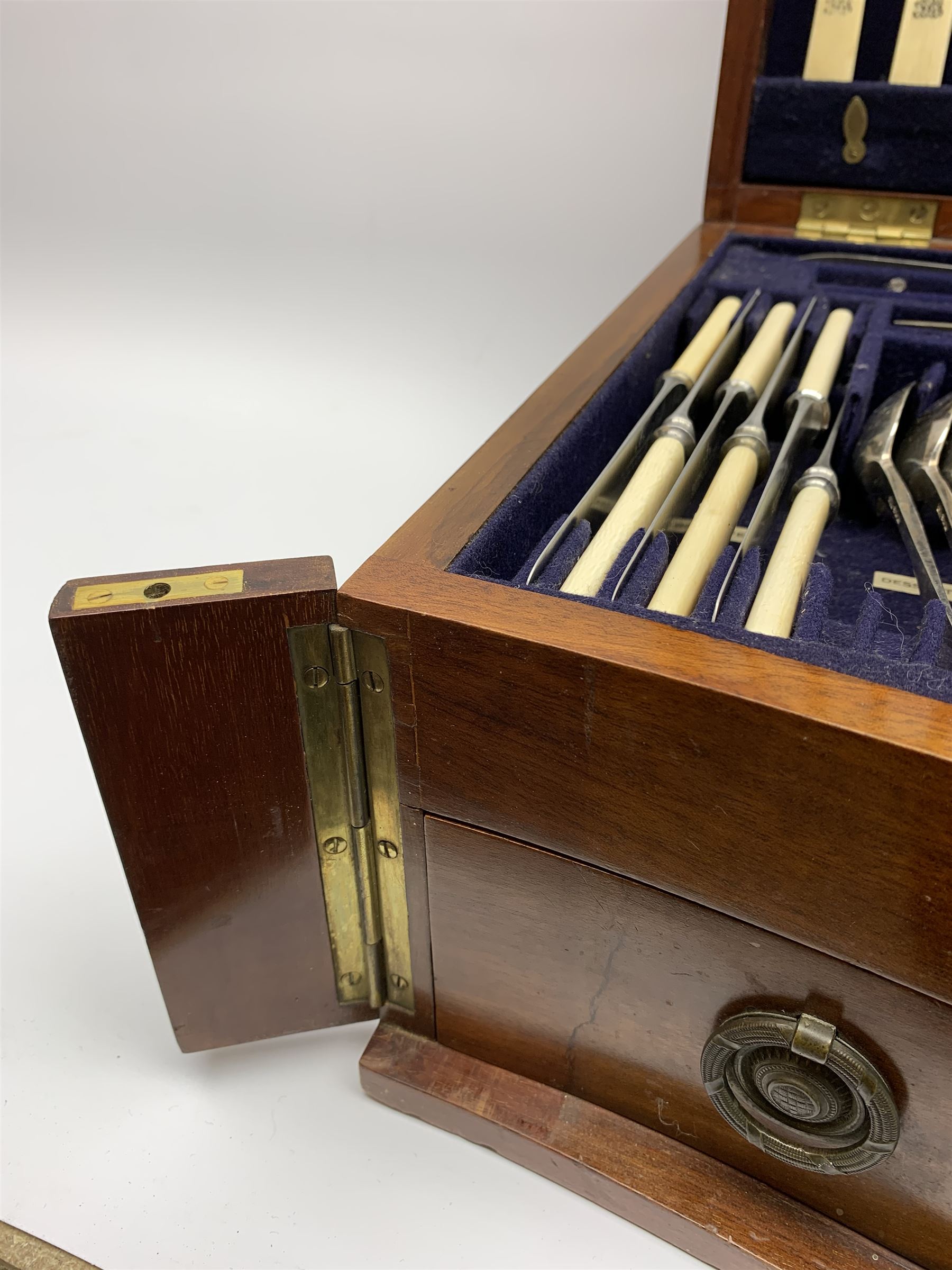 Late 19th/early 20th century composite canteen of silver flatware, contained within an early 20th century mahogany serpentine fronted case with twin drop carry handles, and hinged cover with boxwood stringing and central inlaid shell motif, above a single drawer with twin ring handles and Wellington style locking system, the cover and drawer opening to reveal plaque for Spink & Sons Ltd London, and fitted interior containing ivory handled knives, ivory handled carving set, and silver Hanoverian and Old English pattern cutlery, each with engraved monogram to terminal, hallmarked London, makers Spink & Son (John Marshall Spink), Goldsmiths & Silversmiths Co, and Chawner & Co (George William Adams), various dates ranging 1880-1923, gross weighable silver 92.59 ozt (2880 grams)