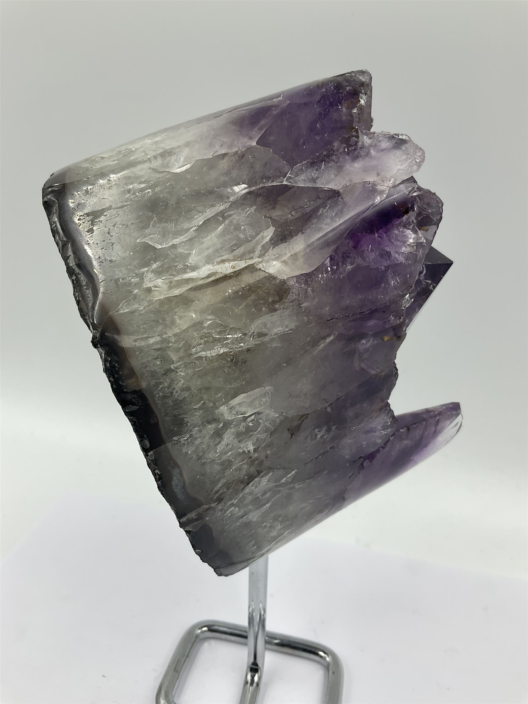 Amethyst crystal geode cluster, with large well-defined crystals, upon a metal stand, H21cm