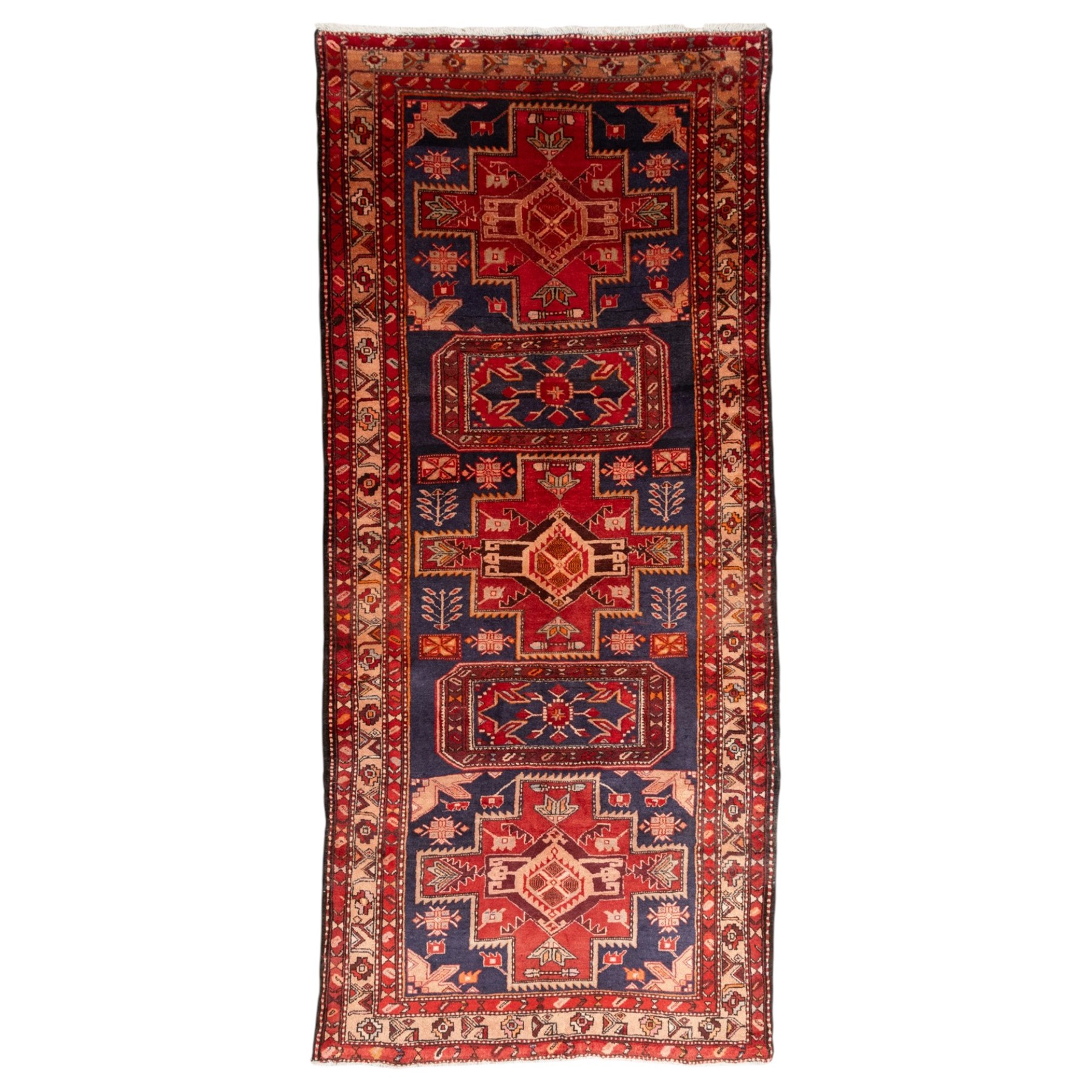 North West Persian runner, the indigo field decorated with three stepped cruciform medallions alternating with two octagonal panels, interspersed with stylised flowerheads and foliage, enclosed by an ivory ground floral border and red guard bands