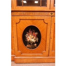  Sheraton Revival satinwood breakfront bookcase, frieze painted with scrolling leafage above four astragal doors with adjustable shelves, the base with four doors painted with floral sprays in oval panels, on a plinth base, W234cm, H235cm, D52cm  