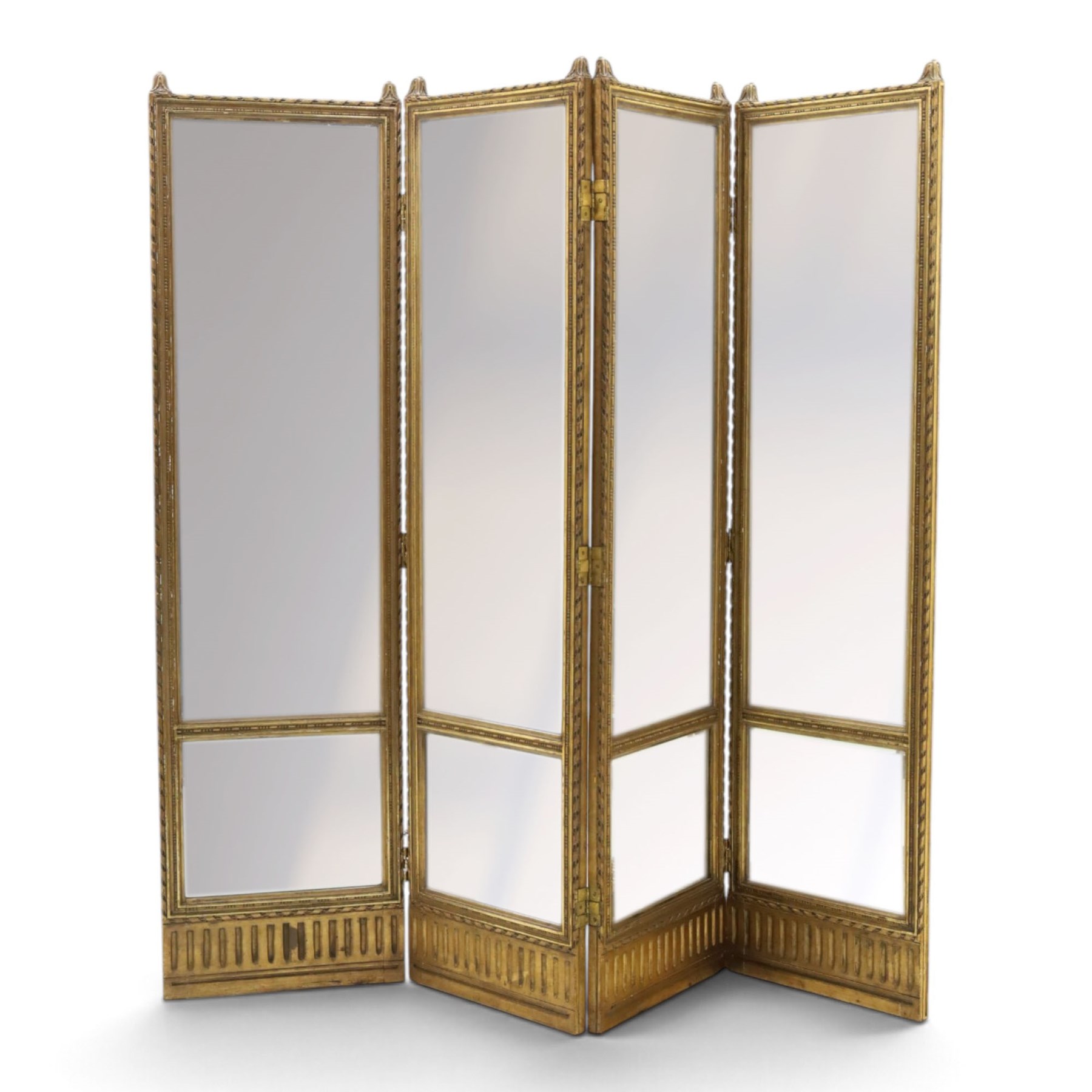 Early 20th century gilt and bevelled mirrored four panel folding screen, with two mirrors per side, flanked by beaded edges and scrolled finials, arcaded carved frieze