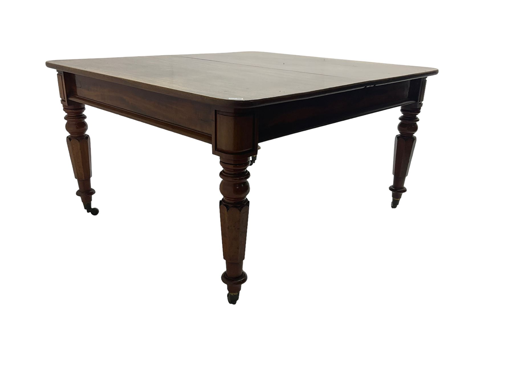 Late 19th century extending mahogany dining table, square top with banded frieze rail, raised on turned octagonal supports with  brass cups and castors, with two additional leaves