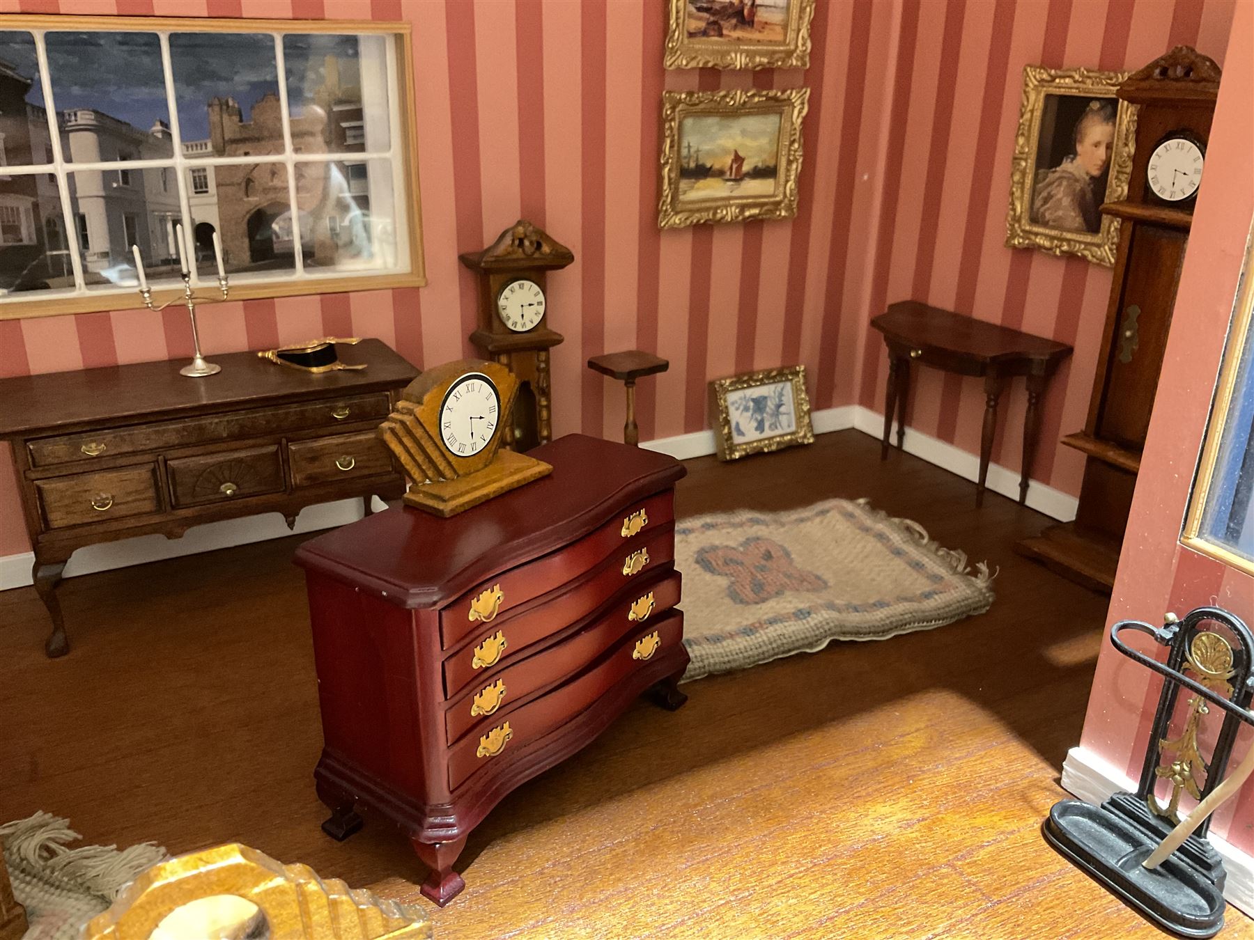 Good quality late 20th century dolls house by M. James dated 1995 in the form of a Beverley East Yorkshire Antique Shop called 'North Bar Antiques'; single-storey single-roomed shop with textured brick walls and flat roof, fully glazed hinged front with recessed hinged customer door and central window to the rear; comprehensively furnished with chests of drawers, pedestal desk, breakfast table, lowboy, two longcase clocks, delft rack with ceramics, occasional tables, pictures, Regency style mirror and collectibles; decorated walls with coving and picture rail and simulated floorboarding; wired for electric lighting; maker's plaque W61cm H42.5cm D41.5cm