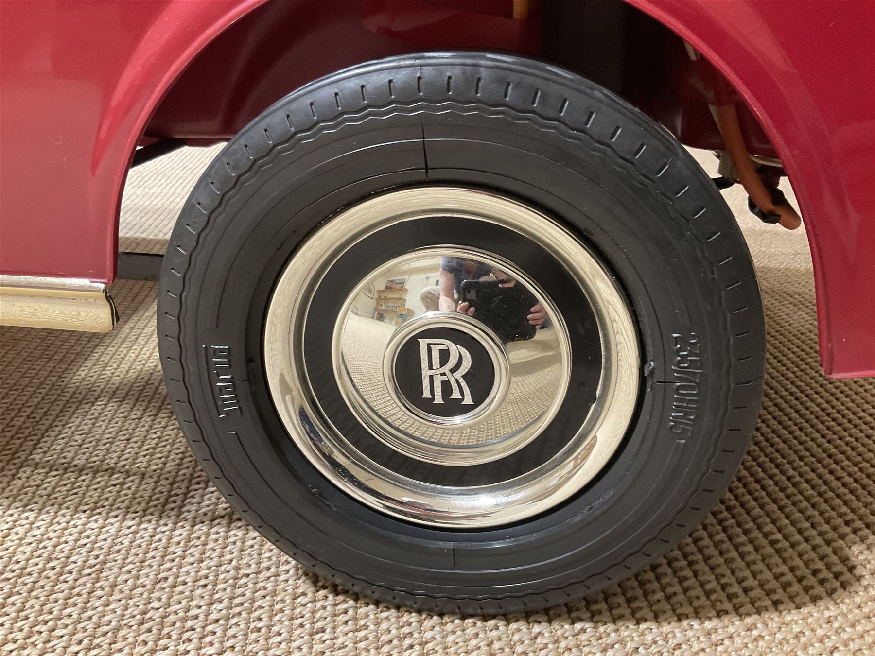 Early 1980s Rolls-Royce Corniche 'pedal' car by Sharna Tri-ang Limited, registration no.RRM1, steel chassis with treadle pedals, red moulded plastic body with flexible plastic 'Spirit of Ecstasy' car mascot on the radiator cap, opening boot lid, dashboard with decals of faux wood panelling and gauges, battery powered working electric lights, Sharna 235/70HR15 wheels with Rolls Royce hub caps, L123cm; together with two keys on RR fob, instructions manual in wallet, date stamped 17 November 1983, toy road tax disc dated 31.01.83/84 and original battery charger. 
Auctioneers Note: In 1983 Sharna Tri-ang Ltd., based at Lumb Mill in Droylsden, Manchester, took over from Tri-ang Toys at Merthyr Tydfil. They went on to launch a new range of toys based on children's TV programs, such as Knight Rider, Street Hawk, Roland Rat, The A-Team, The Get A-Long Gang and Postman Pat, as well as Rolls-Royce Corniche pedal cars, which were available in red, white or blue. 
