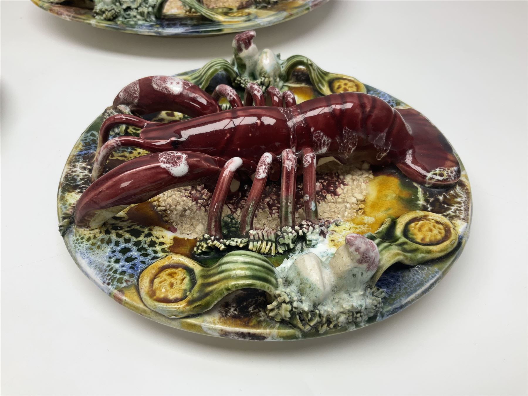 Five 20th Century Portuguese Palissy style Majolica wall plates, all depicting crustaceans to the centre modelled in relief surrounded by encrustations and shells, both with impress marks beneath, largest D29cm