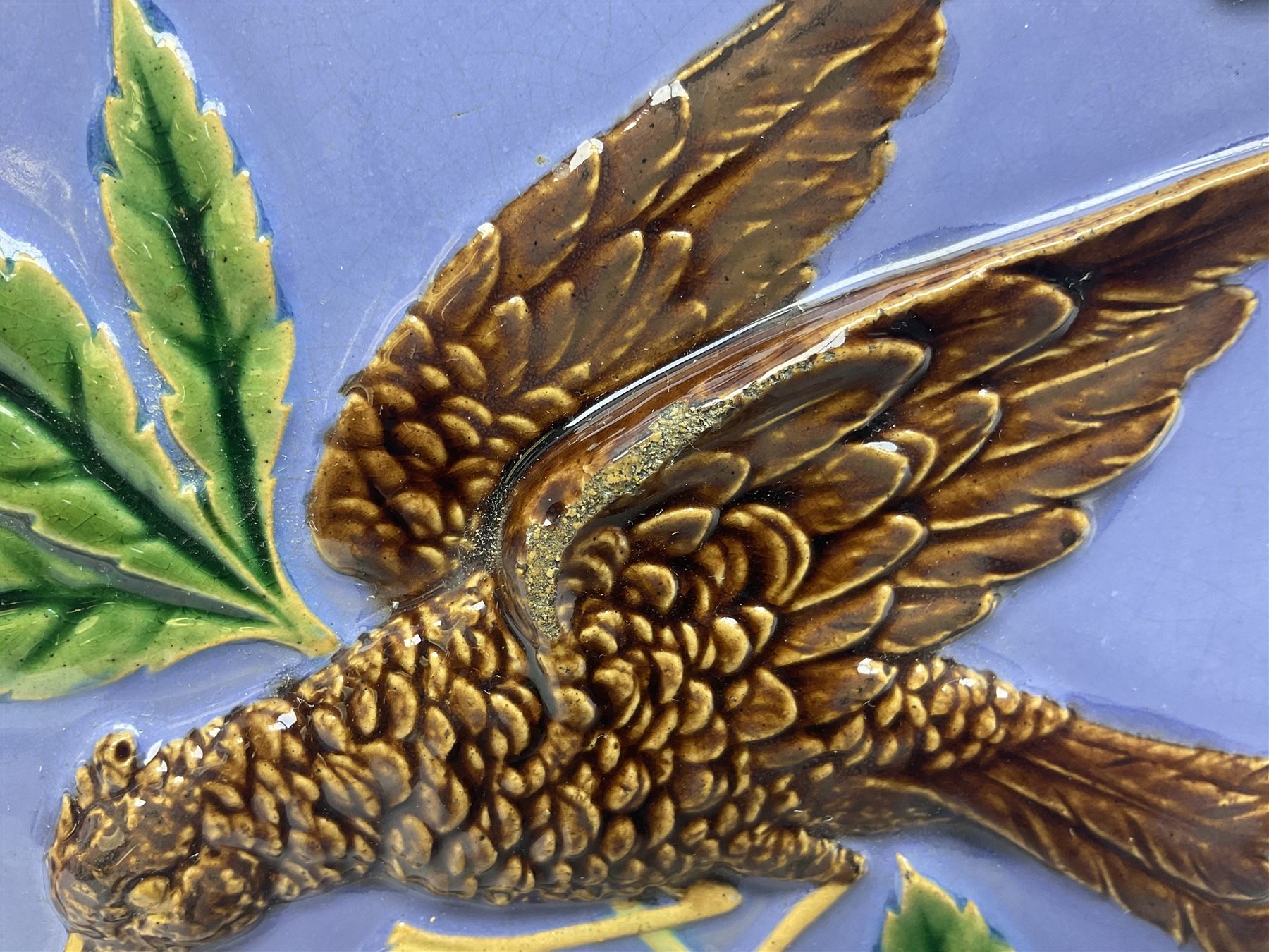 19th century Minton & Co majolica tile, decorated in relief with a bird upon a fruiting branch against a blue ground, with textured ochre border and anthemion to each corner, impressed mark verso, H19.7cm