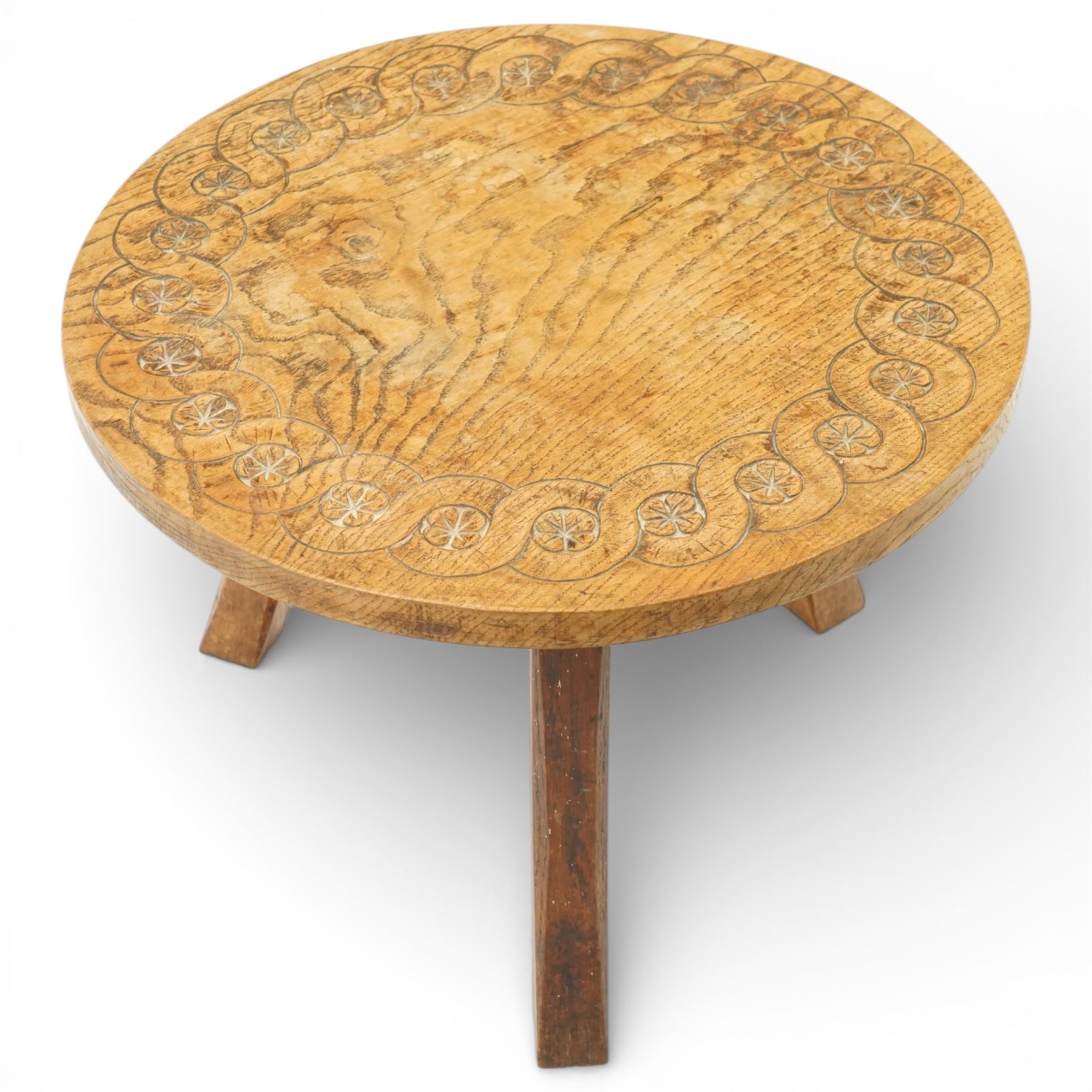Gnomeman - oak circular stool, the top carved with continuous rosette and scrolling border, raised on three splayed supports, one leg carved with gnome signature, by Thomas Whittaker of Littlebeck