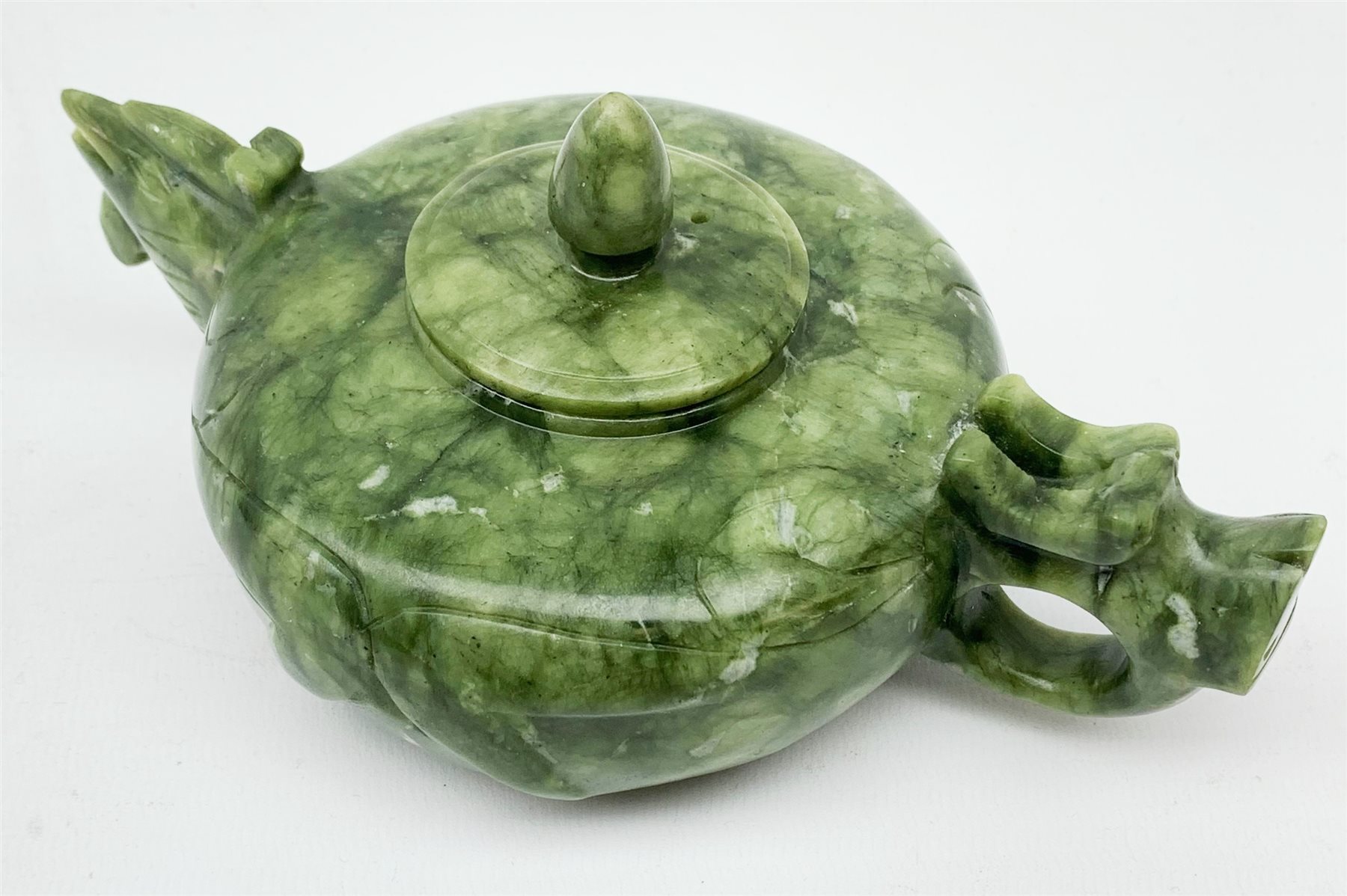 A carved jade teapot, the spout modelled as the head of a bird, the handle modelled as a stylised dragons head, H7.5cm. 