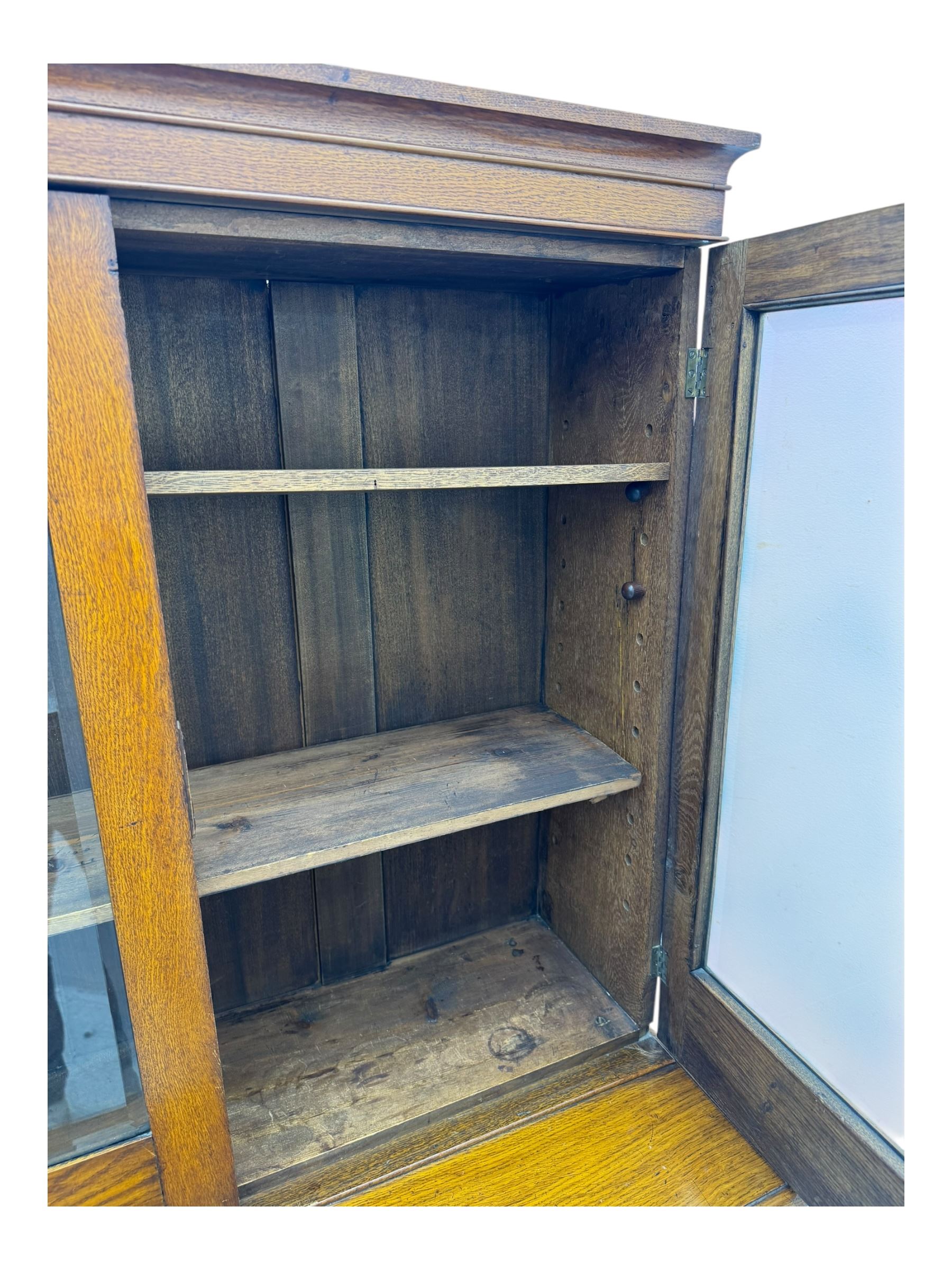 Late 19th century oak display cabinet, rectangular form with a pair of glazed doors enclosing shelves, raised on cabriole supports with carved detailing ending in claw feet