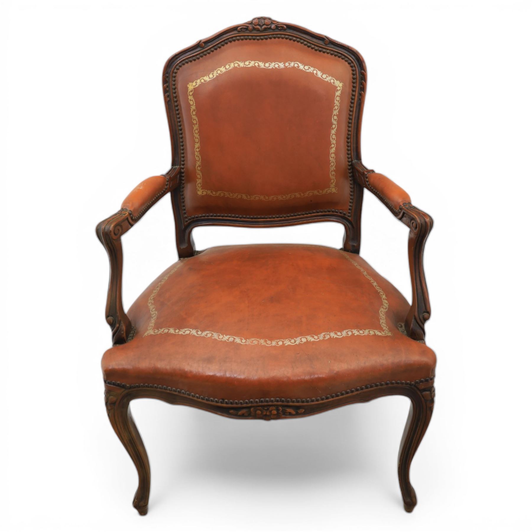 Pair of late 20th century French style carved beech open armchairs, the shaped and moulded frames with foliate cresting rail above padded backs and overstuffed seats upholstered in tan leather with gilt foliate borders and close nailed trim, raised upon cabriole supports with acanthus carved knees