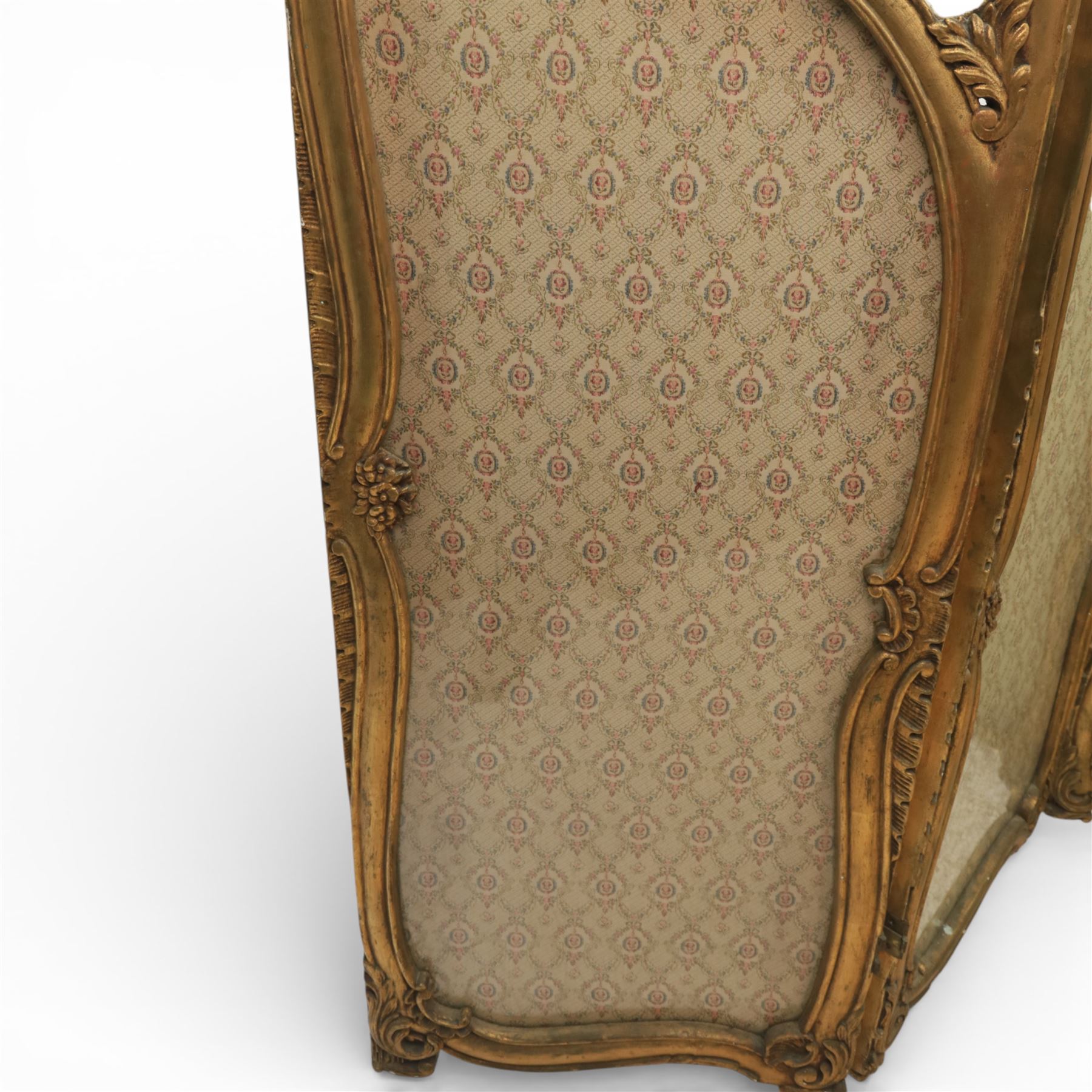 Rococo style giltwood three-panel dressing screen, each panel with shaped and scroll carved frame decorated with shell and foliate motifs, the upper sections glazed, the lower sections upholstered in patterned fabric, hinged to form a folding screen