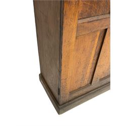The North of England School Furnishing Company Limited Darlington - early 20th century oak school cupboard, projecting moulded cornice over two panelled doors, fitted with shelves, on chamfered plinth base 