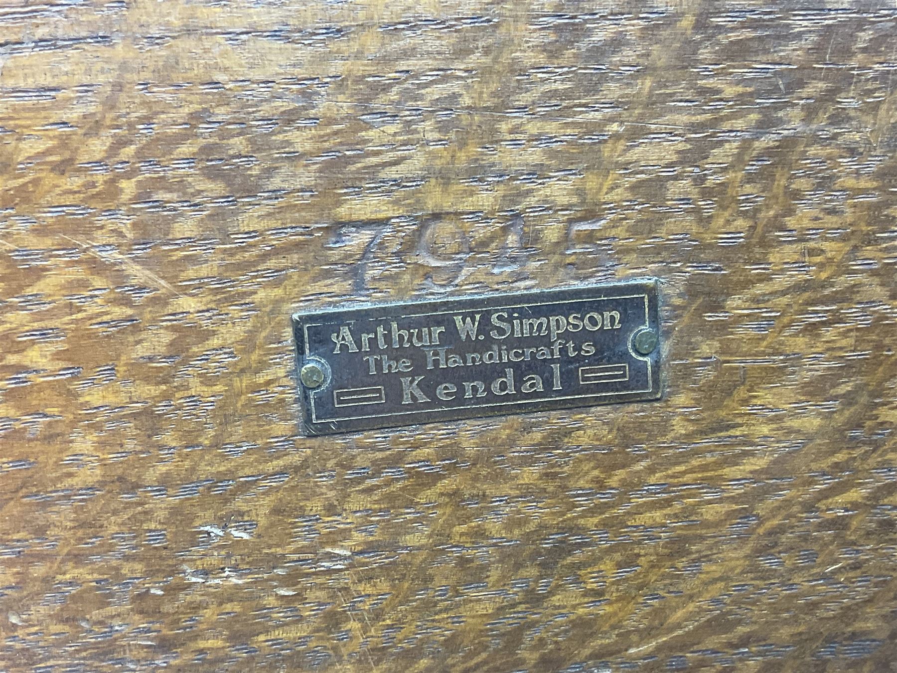 Arts and Crafts oak stand by Arthur Simpson of Kendal, of rectangular form with central hammered pewter panel, surrounded by a border with carved foliate corners, upon two bar supports, bearing label detailed 