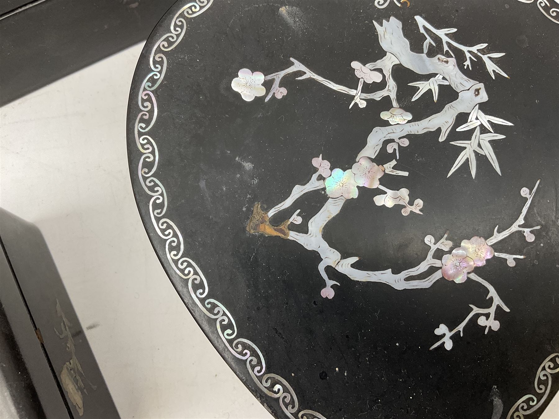  Late 19th / early 20th century Japanese lacquered table top cabinet, heavily decorated with mother of pearl inlay depicting blossoming branches, flowers and birds, the two hinged doors between longer drawers opening to reveal interior fitted with four short drawers, with lift up hinged canted lid, H28cm D9.5cm W23cm, together with mother of pearl inlaid miniature folding screen, dish decorated with walking figures with crimped edge, boxes decorated with flowers, birds and gilt etc