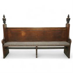 Late 19th century Gothic revival oak church pew, with high backrest framed by carved stylised cross panels and crown-topped finials, shaped end panels with scroll detailing, on block end supports and central stretcher, with later padded seat cushion
