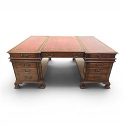 George III style large mahogany reverse breakfront partners desk, red tooled leather writing surfaces crossbanded and moulded edges, flanked by ring-turned cluster columns three frieze drawers with brass swan neck handles, raised on large pedestals with faux drawer fronted cupboard and three graduated drawers, supported on carved ogee feet decorated with C-scrolled and acanthus leaves