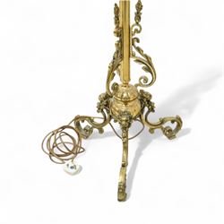 Late Victorian brass standard lamp with shade, slender column with blooming lotus leaf floral base with raised acanthus leaf scrolls above a tripod stand with scroll legs 