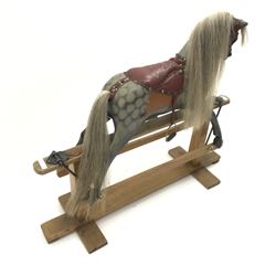 Early 20th century dapple grey rocking horse, leather rein and saddle with stirrups on trestle base