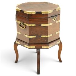 Late 18th century Anglo-Indian padouk and brass-bound octagonal cellarette or wine cooler, the hinged lid enclosing a vacant interior, the panelled body with applied brass strapwork, pierced escutcheon and side carrying handles, raised on a separate stand terminating to four fluted and reeded cabriole supports