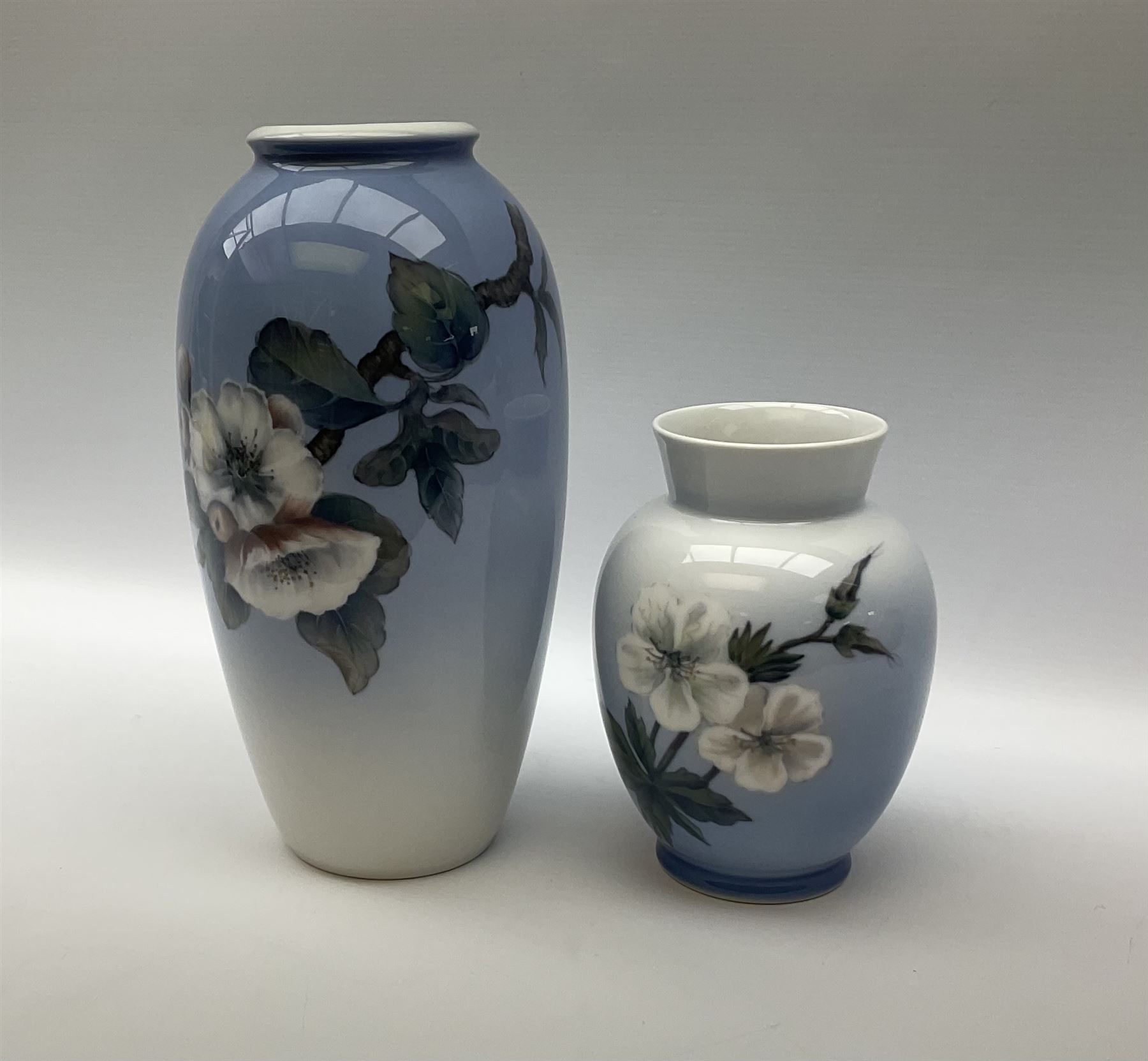 Two Royal Copenhagen vases, first example a vase of baluster form with apple blossom design on a pale blue ground, model no 2629 design no 2129 H27.5cm, second example a vase of ovoid form, with flower and butterfly decoration, model no 2667 design no 36 H17.5cm. 