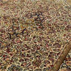 Fine Qom hand-knotted rug, ivory ground, with a dark navy shaped floral medallion and pendants, the field densely worked with fine flowering vines, palmettes and leafy scrolls in red, green, ochre and blue tones, within golden spandrels and a dark navy floral border, flanked by narrow guard stripes, with cotton fringes