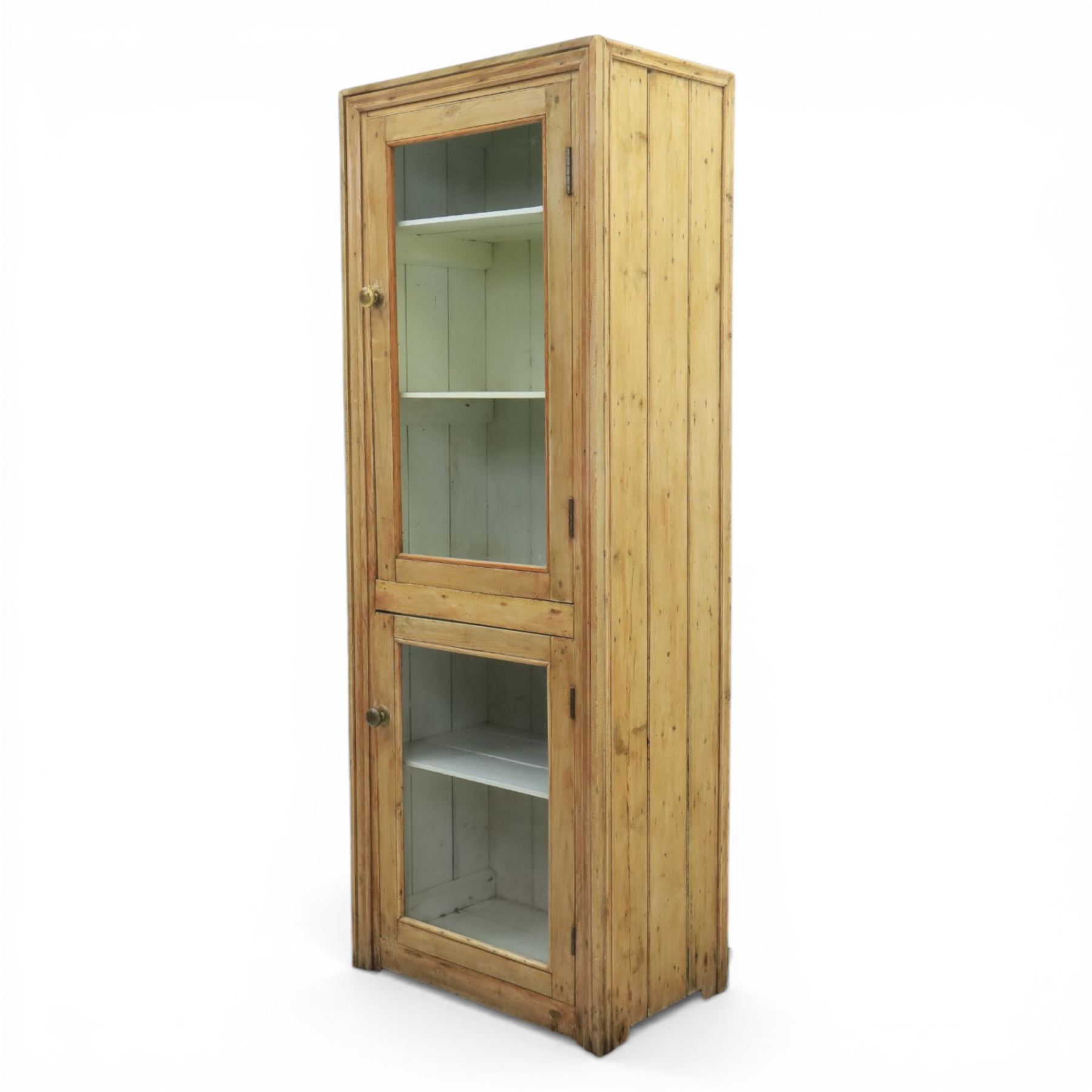 Early 20th century waxed pine kitchen cupboard, rectangular form with moulded top, enclosed by two glazed doors revealing painted interior with shelves, boarded sides and back, fitted with brass knob handles